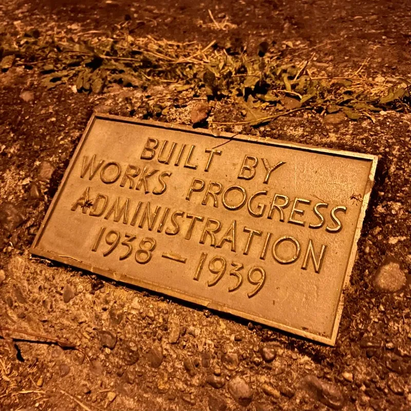 A Built by Works Progress Administration Plaque embedded in the sidewalk in Bremerton&#x27;s Union Hill neighborhood at night under the glow of the street lights