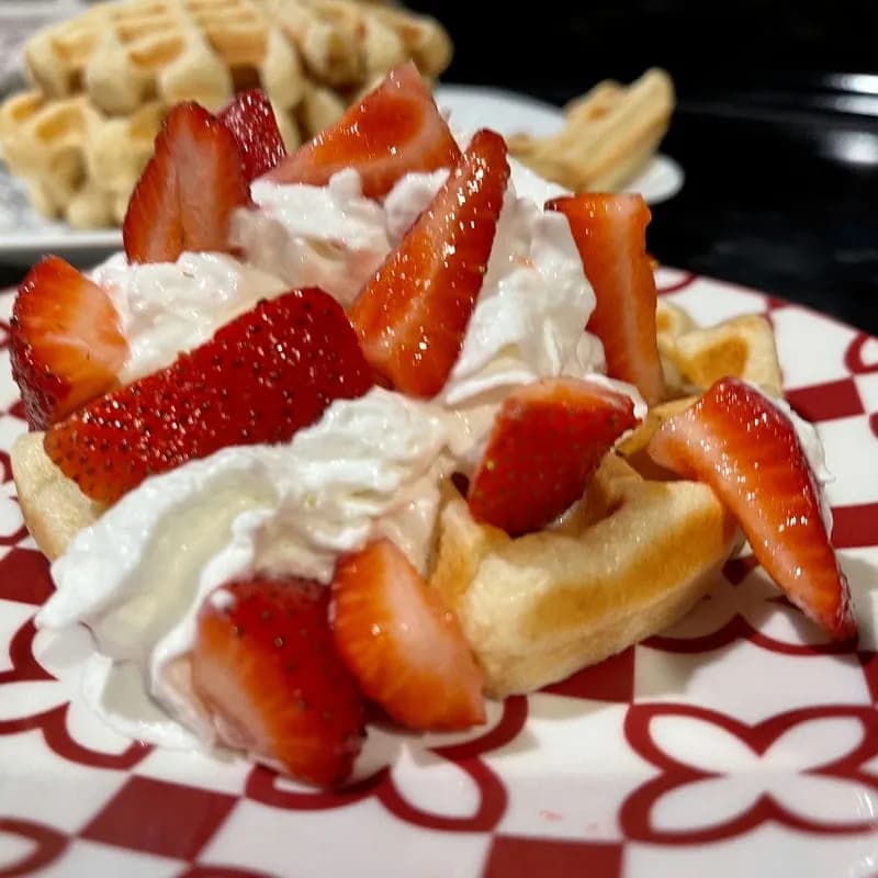 delicious looking waffle smothered in strawberries and whipped cream